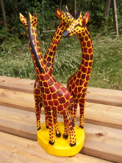 Group of three carved wooden giraffes on a stump